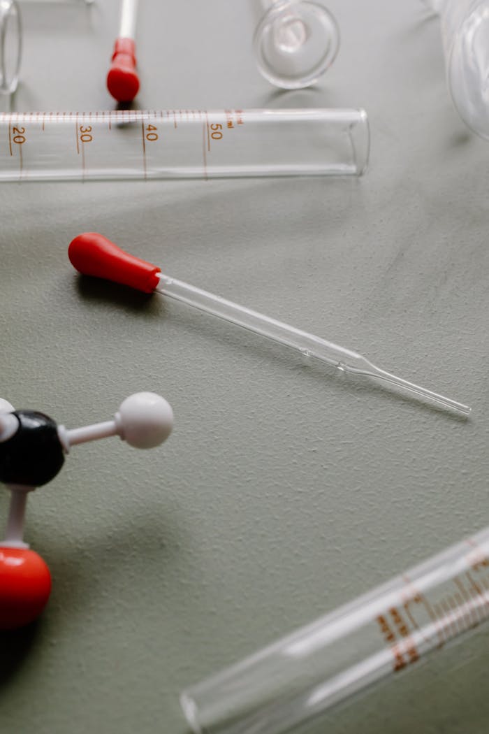 Close-up of glass dropper and test tubes in a scientific laboratory setup.